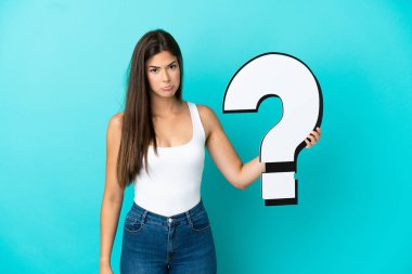 Mavi arka planda izole edilmiş genç Brezilyalı kadın elinde bir soru işareti simgesi tutuyor ve üzgün bir ifadeyle