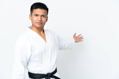Genç Ekvadorlu adam beyaz arka planda karate yapıyor. Davet etmek için ellerini yana uzatıyor.