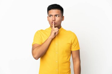 Beyaz arka planda izole edilmiş genç Ekvadorlu bir adam sessiz bir jest işareti gösteriyor. Parmağını ağzına sokuyor.