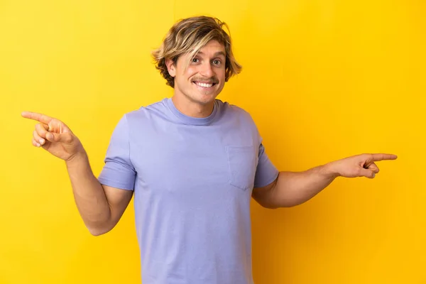 Handsome Blonde Man Isolated Yellow Background Pointing Finger Laterals Happy — Fotografia de Stock