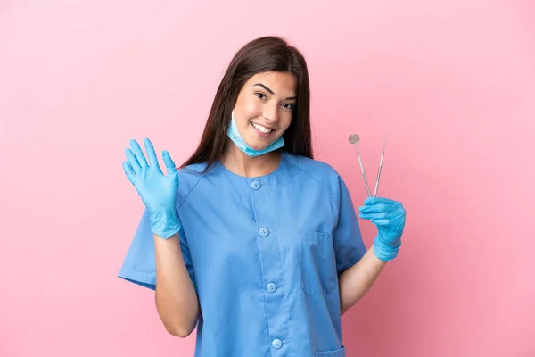 Dentystka Trzyma Narzędzia Odizolowane Różowym Tle Salutując Ręką Szczęśliwym Wyrazem — Zdjęcie stockowe