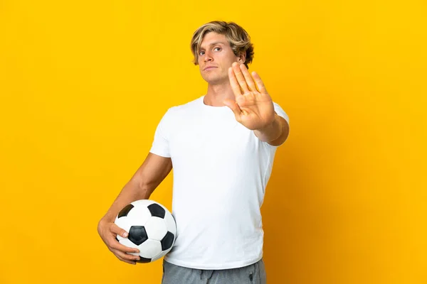 Jogador de futebol forte com bola de futebol e sorrindo em fundo branco  isolado