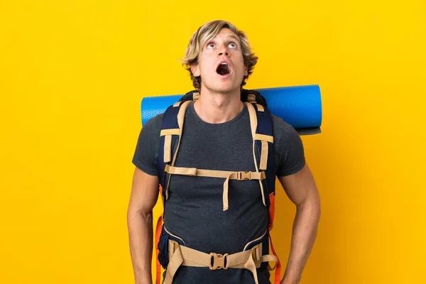 Joven Montañero Sobre Fondo Amarillo Aislado Mirando Hacia Arriba Con — Foto de Stock