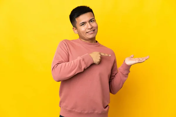 Young Ecuadorian Man Isolated Yellow Background Holding Copyspace Imaginary Palm — Stock Fotó