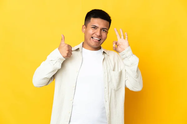 Young Ecuadorian Man Isolated Yellow Background Showing Sign Thumb Gesture — Foto de Stock