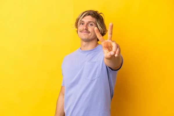 Bonito Loira Homem Isolado Fundo Amarelo Sorrindo Mostrando Sinal Vitória — Fotografia de Stock