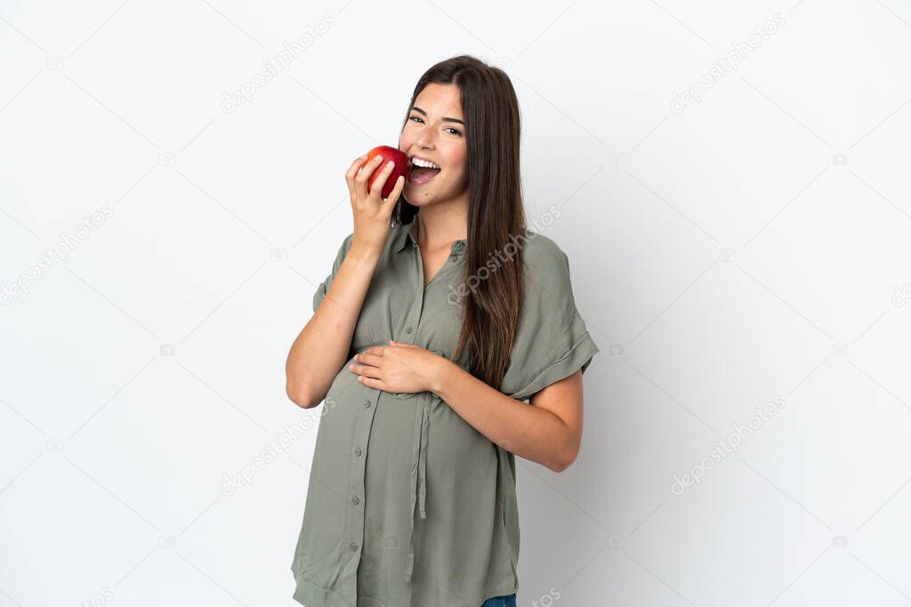 Young Brazilian woman isolated on white background pregnant and holding an apple and eating it