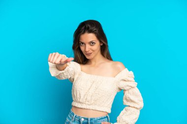 Mavi arka planda izole edilmiş beyaz bir kadın baş parmak işareti yapıyor.