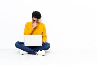 Venezuelalı adam dizüstü bilgisayarla oturmuş gülüyor.