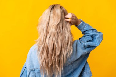 Genç Rus kadın sarı arka planda izole edilmiş ve düşünüyor.