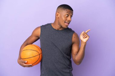 Mor arka planda izole edilmiş genç basketbolcu parmağını kaldırarak çözümü bulmayı umuyor.