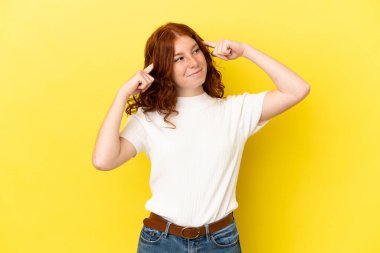 Genç kızılımsı kadın sarı arka planda izole edilmiş. Şüpheleri ve düşünceleri var.