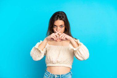 Mavi arka planda izole edilmiş beyaz bir kadın sessizlik işareti gösteriyor.
