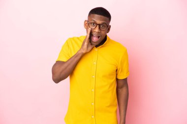 Pembe arka planda mahsur kalmış genç latin adam şaşırmış ve şok olmuş bir yüz ifadesiyle