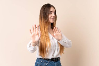 Beyazlı genç bir kadın bej arka planda izole edilmiş gergin eller öne doğru uzanıyor.