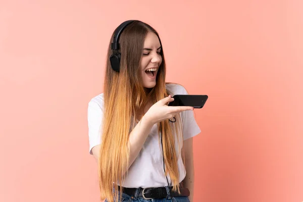 Giovane Donna Caucasica Isolata Sfondo Rosa Ascoltare Musica Con Cellulare — Foto Stock