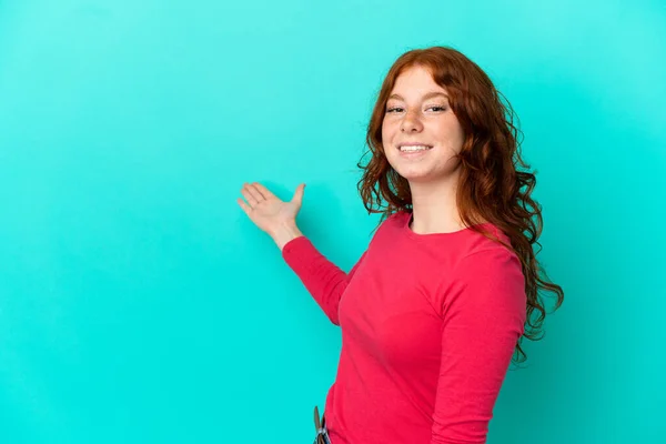 Adolescente Mulher Avermelhada Isolado Fundo Azul Estendendo Mãos Para Lado — Fotografia de Stock