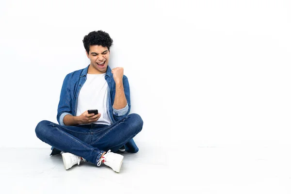 Venezolaner Sitzt Mit Handy Siegerpose Auf Dem Boden — Stockfoto