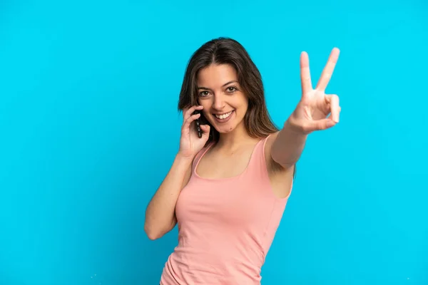 Giovane Donna Caucasica Utilizzando Telefono Cellulare Isolato Sfondo Blu Sorridente — Foto Stock