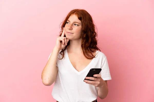 Teenager Reddish Woman Isolated Pink Background Using Mobile Phone Thinking —  Fotos de Stock