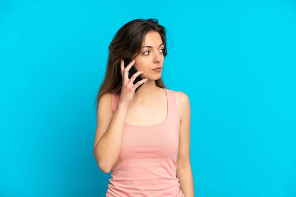 Giovane Donna Caucasica Utilizzando Telefono Cellulare Isolato Sfondo Blu Guardando — Foto Stock