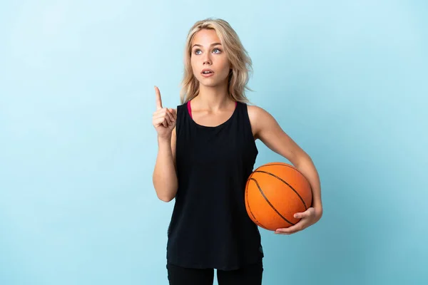 年轻的俄罗斯女子打篮球时被蓝色背景隔离了 她认为这是一个指指点点的想法 — 图库照片