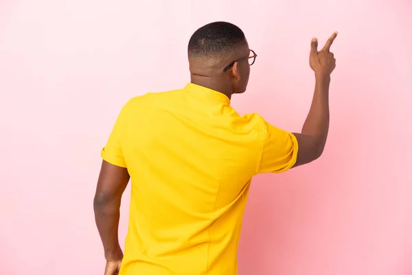 Jovem Latino Isolado Fundo Rosa Apontando Para Trás Com Dedo — Fotografia de Stock