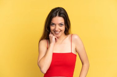 Sarı arka planda izole edilmiş genç beyaz kadın gülüyor.