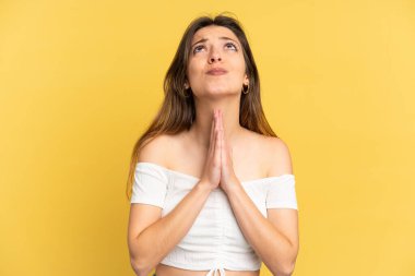 Sarı arka planda izole edilmiş genç beyaz kadın avuç içlerini bir arada tutuyor. İnsan bir şey ister.