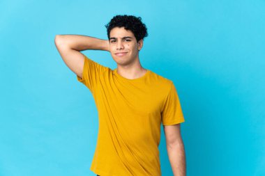 Genç Venezuelalı bir adam mavi arka planda izole edilmiş.