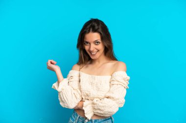 Mavi arka planda izole edilmiş genç beyaz kadın gülüyor.