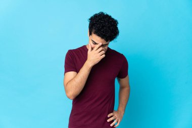 Genç Venezuelalı adam mavi arka planda izole edilmiş gülüyor.