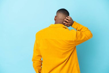 Genç latin adam mavi arka planda izole edilmiş ve düşünüyor