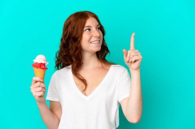 Kornet dondurmalı genç bir kadın mavi arka planda izole edilmiş harika bir fikre işaret ediyor.