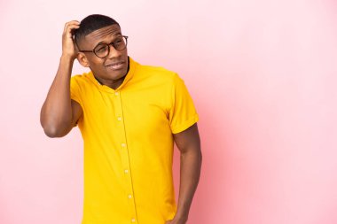 Pembe arka planda izole edilmiş genç latin adamın şüpheleri ve kafa karıştırıcı bir yüz ifadesi var.