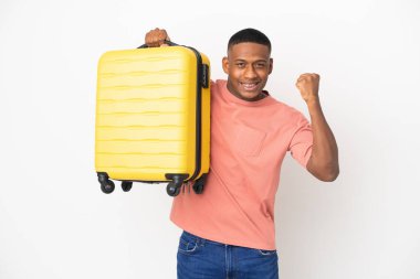 Beyaz arka planda izole edilmiş, seyahat valiziyle gezen genç Latin bir adam.