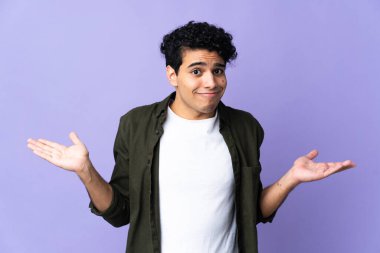 Genç Venezuelalı bir adam mor arka planda izole edilmiş, şüpheli hareketler yapıyor.