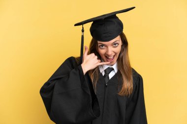 Young university graduate isolated on yellow background making phone gesture. Call me back sign