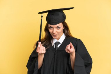 Sarı arka planda izole genç üniversite mezunu para hareketi yapıyor.