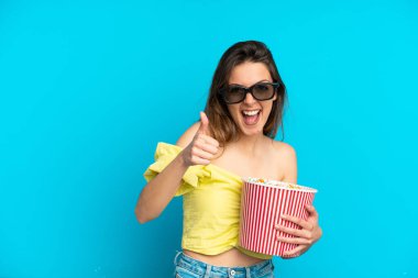 Mavi arka planda 3 boyutlu gözlüklü ve elinde patlamış mısırla gezen beyaz bir kadın.