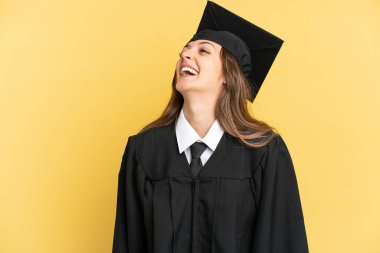 Young university graduate isolated on yellow background posing with arms at hip and smiling