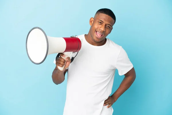 Jovem Latino Isolado Fundo Azul Segurando Megafone Sorrindo — Fotografia de Stock