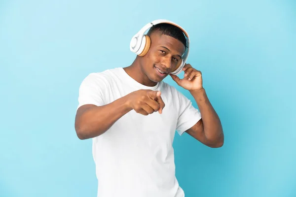 Pemuda Latin Terisolasi Latar Belakang Biru Mendengarkan Musik Dan Menunjuk — Stok Foto