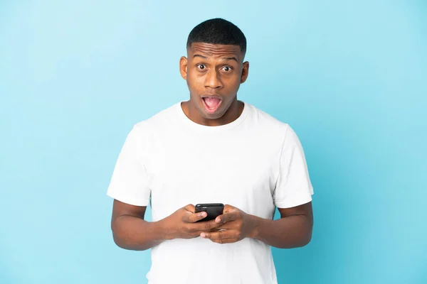 Jovem Latino Isolado Fundo Azul Olhando Para Câmera Usar Celular — Fotografia de Stock