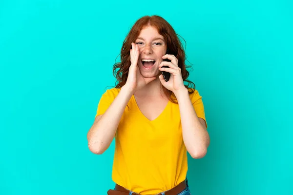 Teenager Načervenalé Žena Pomocí Mobilního Telefonu Izolované Modrém Pozadí Křičí — Stock fotografie