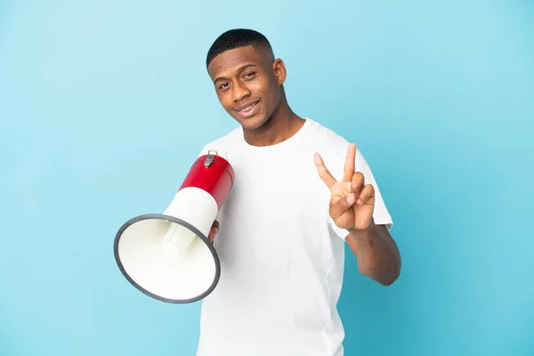 Joven Latino Aislado Sobre Fondo Azul Sosteniendo Megáfono Sonriendo Mostrando —  Fotos de Stock