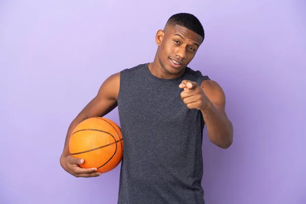 年轻的篮球选手 被紫色背景隔离 惊讶地指着前方 — 图库照片