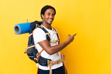 Sarı arka planda izole edilmiş büyük bir sırt çantalı genç dağcı.