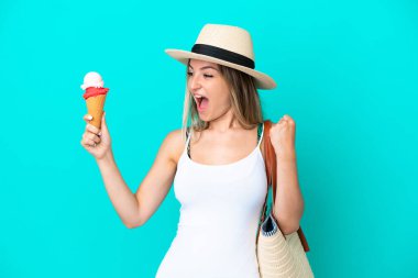 Elinde dondurma ve plaj çantası olan genç Romen kadın mavi arka planda zaferi kutluyor