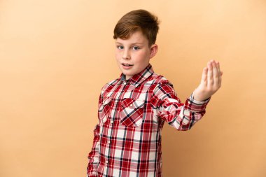 Bej arka planda izole edilmiş küçük kızıl saçlı çocuk bizimle gelmesi için davet ediyor. Gelmene sevindim.